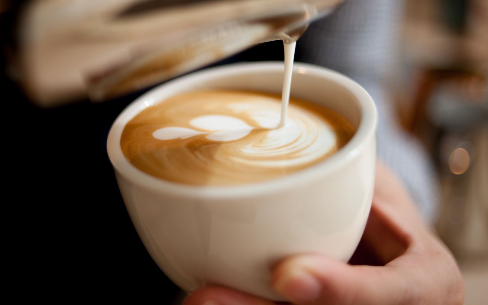 Barista desenhando no leite de um cappuccino