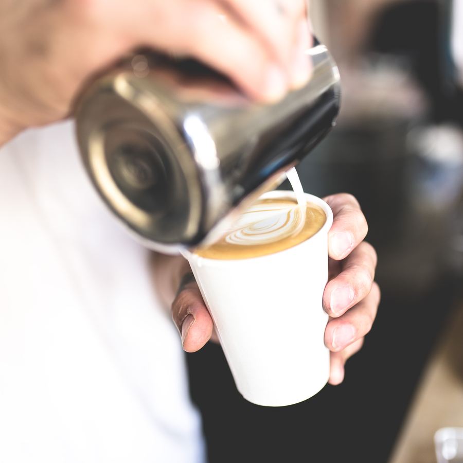 Barista servindo leite vaporizado no copo